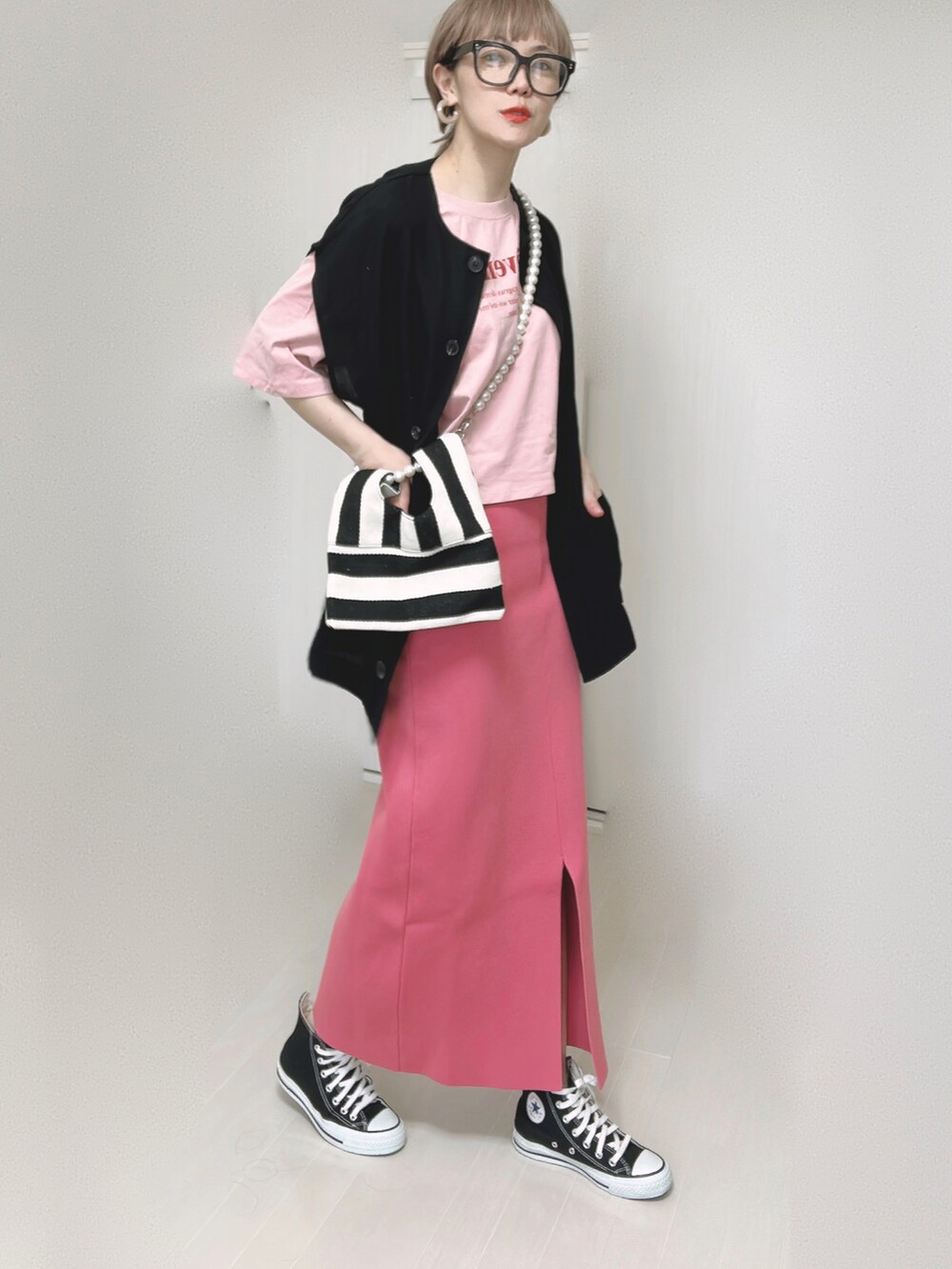 ブラック系のベスト、ホワイト系のショルダーバッグ、ピンク系のスカートを着用したレディースの夏コーディネートの2枚目の写真