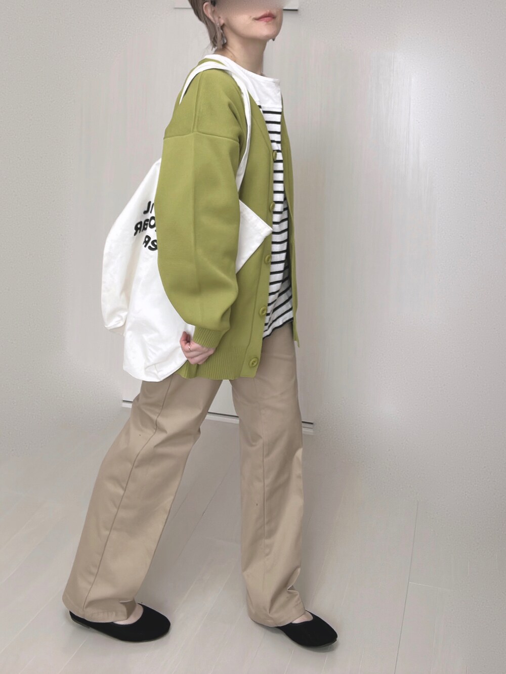 ベージュ系のチノパンツ、グリーン系のカーディガン/ボレロ、ブラック系のTシャツ/カットソーを着用したレディースの冬コーディネートの2枚目の写真