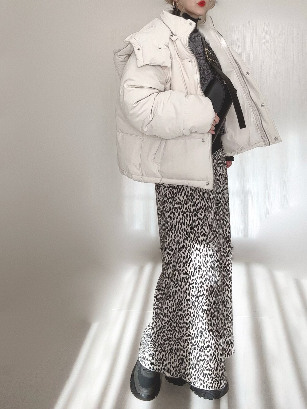 ブラック系のニット/セーター、ブラック系のTシャツ/カットソー、ホワイト系のダウンジャケット/コートを着用したレディースの冬コーディネートの5枚目の写真