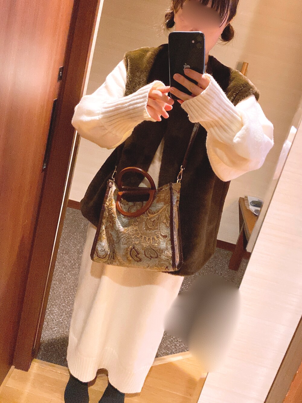 ホワイト系のワンピース、ブラウン系のベスト、グリーン系のショルダーバッグを着用したレディースの冬コーディネートの3枚目の写真