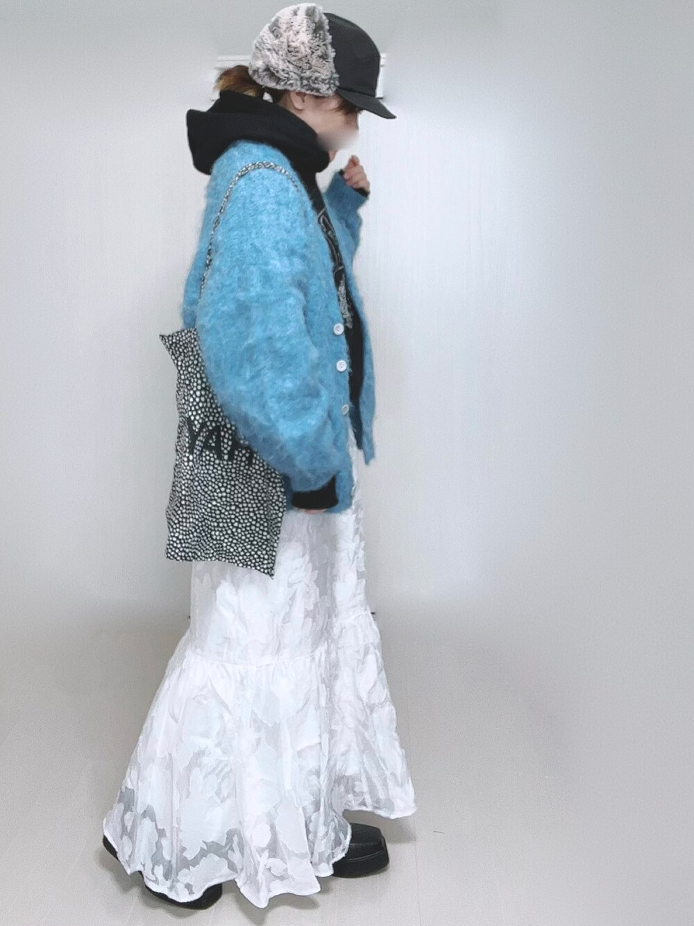 ブラック系のパーカー、ホワイト系のスカート、ブラック系のブーツを着用したレディースの冬コーディネートの5枚目の写真