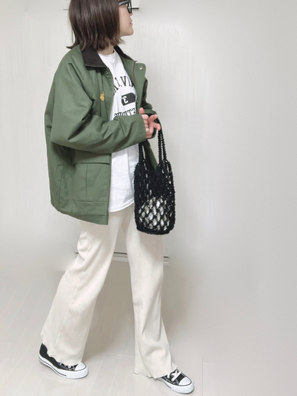 グリーン系のカバーオール、ホワイト系のTシャツ/カットソー、ブラック系のハンドバッグを着用したレディースの春コーディネートの4枚目の写真