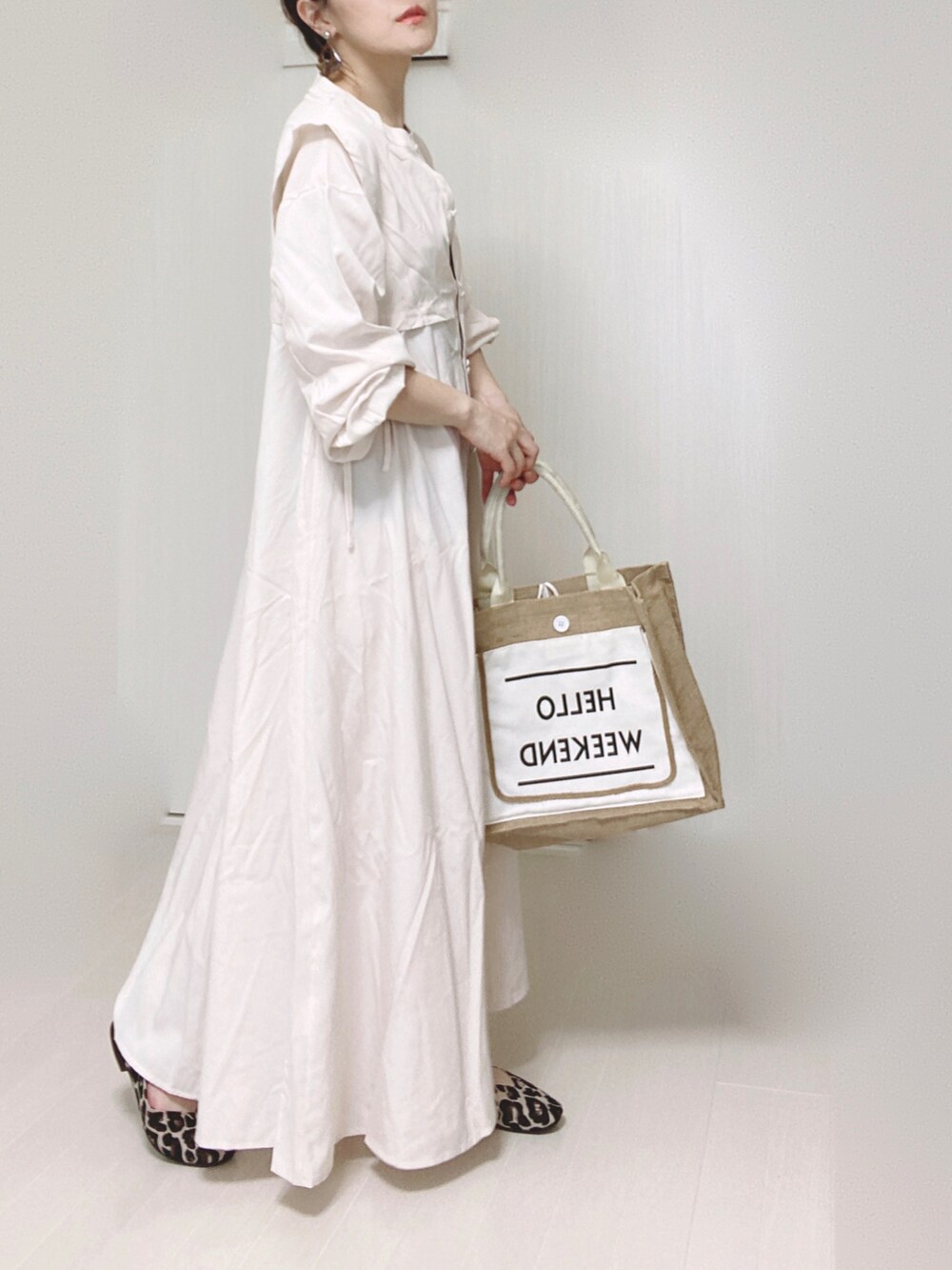 ホワイト系のシャツワンピース、ホワイト系のかごバッグ、ブラウン系のパンプスを着用したレディースの秋コーディネートの2枚目の写真