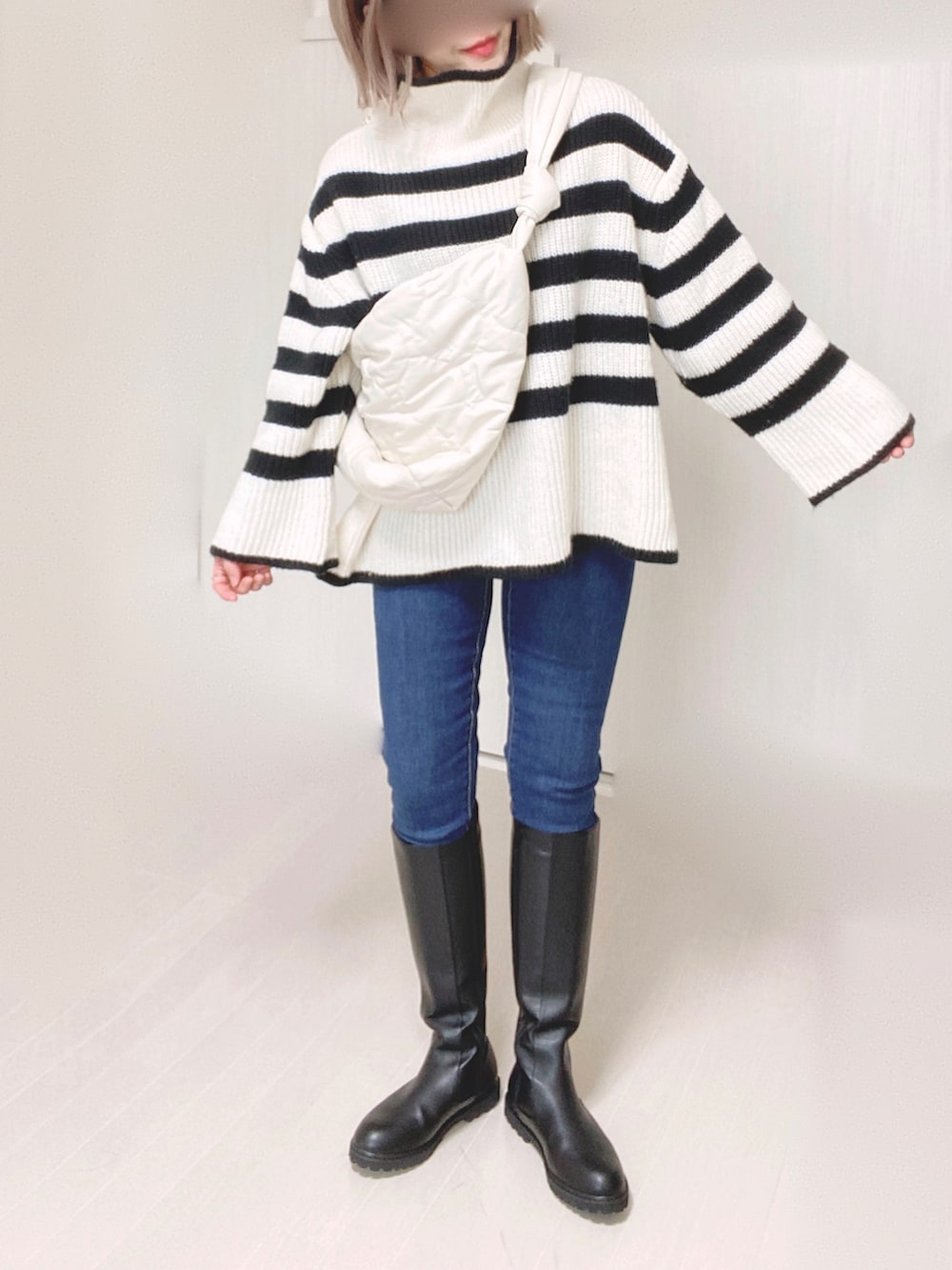 ブラック系のブーツ、ホワイト系のニット/セーター、ホワイト系のショルダーバッグを着用したレディースの秋コーディネートの2枚目の写真