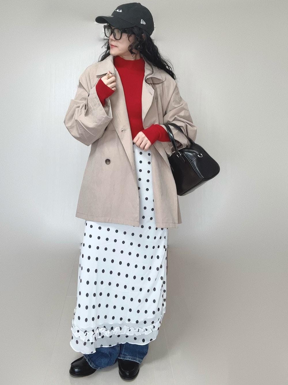レッド系のニット/セーター、ベージュ系のトレンチコート、ブラック系のボストンバッグを着用したレディースの春コーディネートの5枚目の写真
