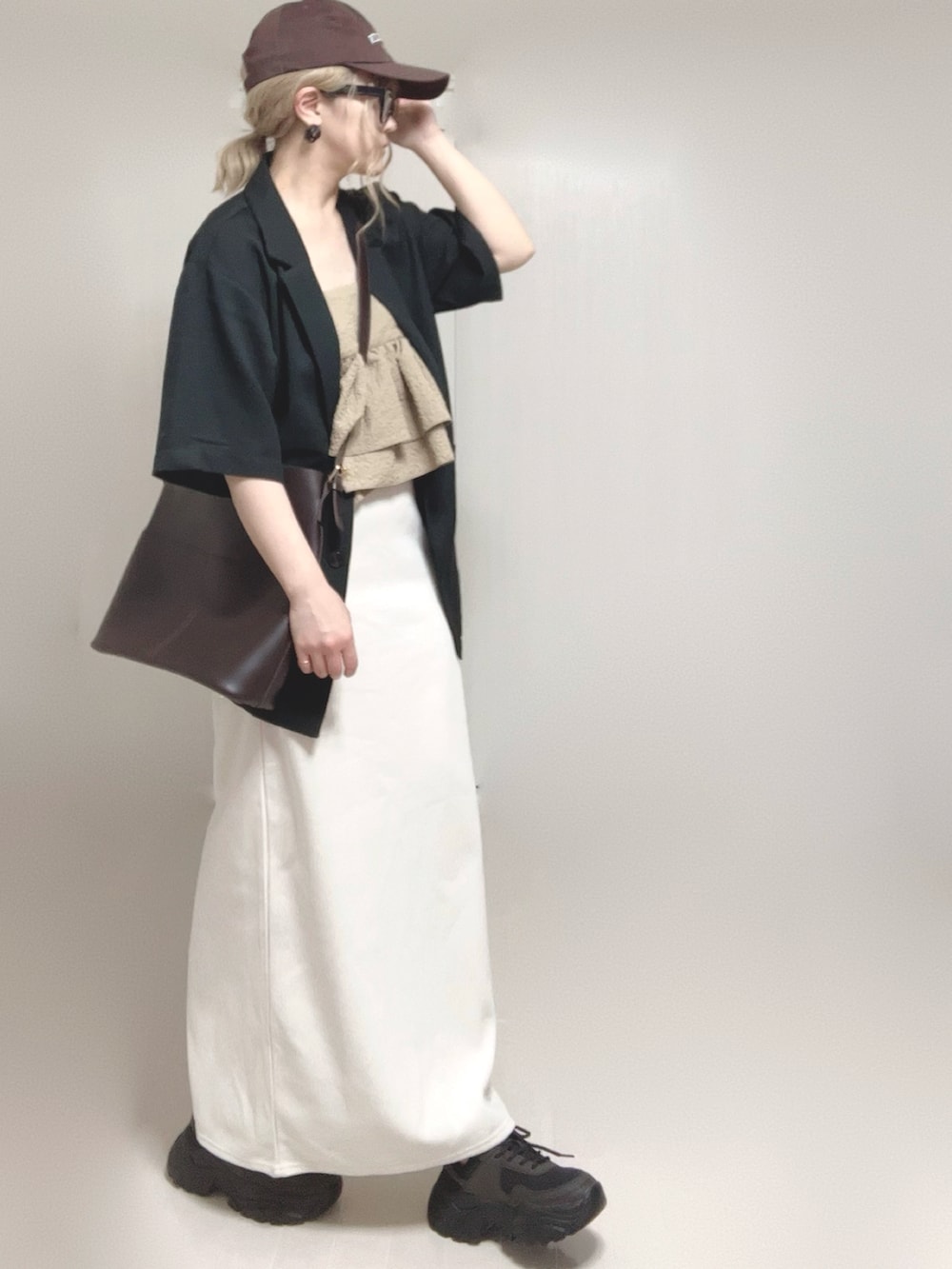ブラック系のテーラードジャケット、ベージュ系のキャミソール、ブラック系のスニーカーを着用したレディースの夏コーディネートの5枚目の写真