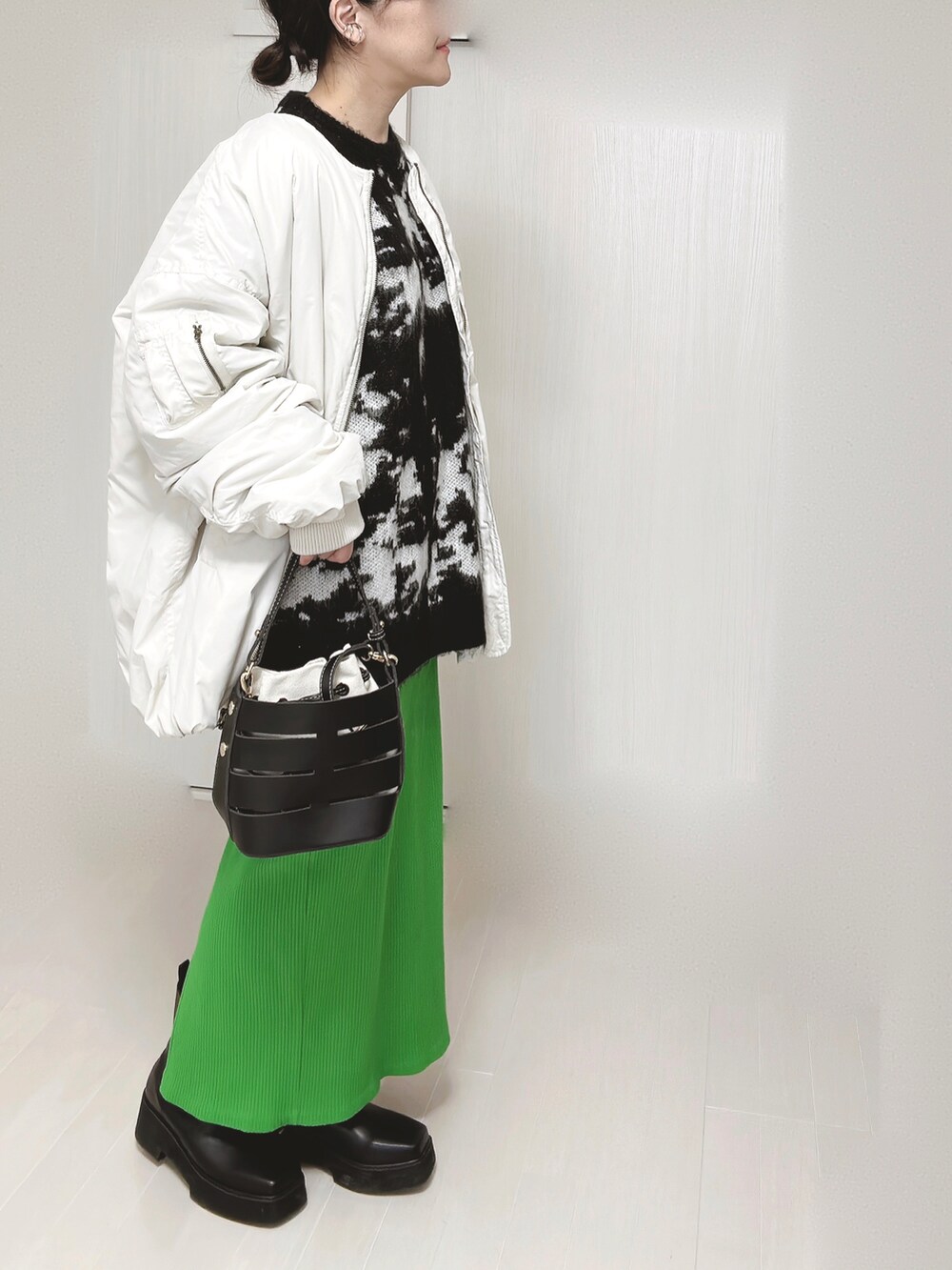 ホワイト系のブルゾン、ブラック系のニット/セーター、ブラック系のショルダーバッグを着用したレディースの冬コーディネートの3枚目の写真