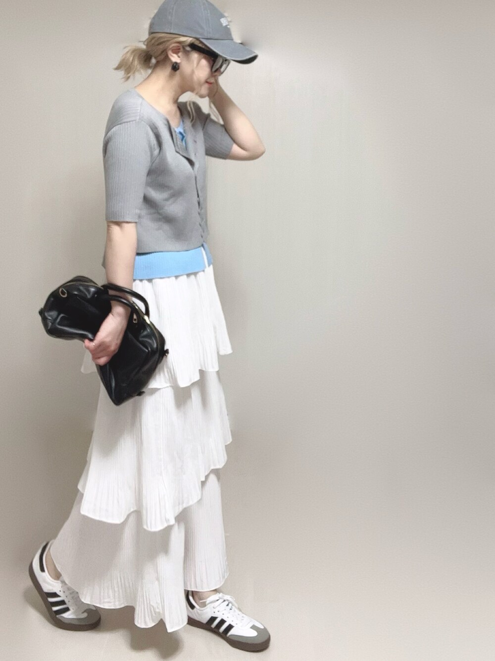 グレー系のニット/セーター、ブラック系のボストンバッグ、ホワイト系のスカートを着用したレディースの夏コーディネートの5枚目の写真