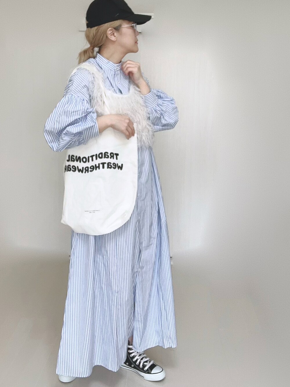 ブルー系のシャツワンピース、ホワイト系のベスト、ホワイト系のトートバッグを着用したレディースの冬コーディネートの4枚目の写真