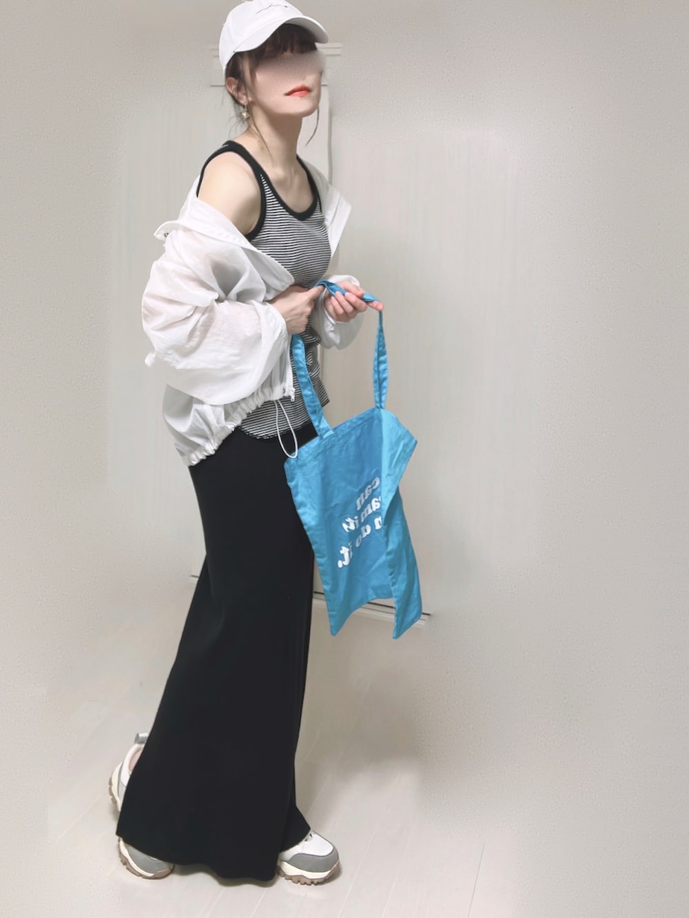 ブラック系のスカート、ブラック系のタンクトップ、ブルー系のトートバッグを着用したレディースの春コーディネートの2枚目の写真
