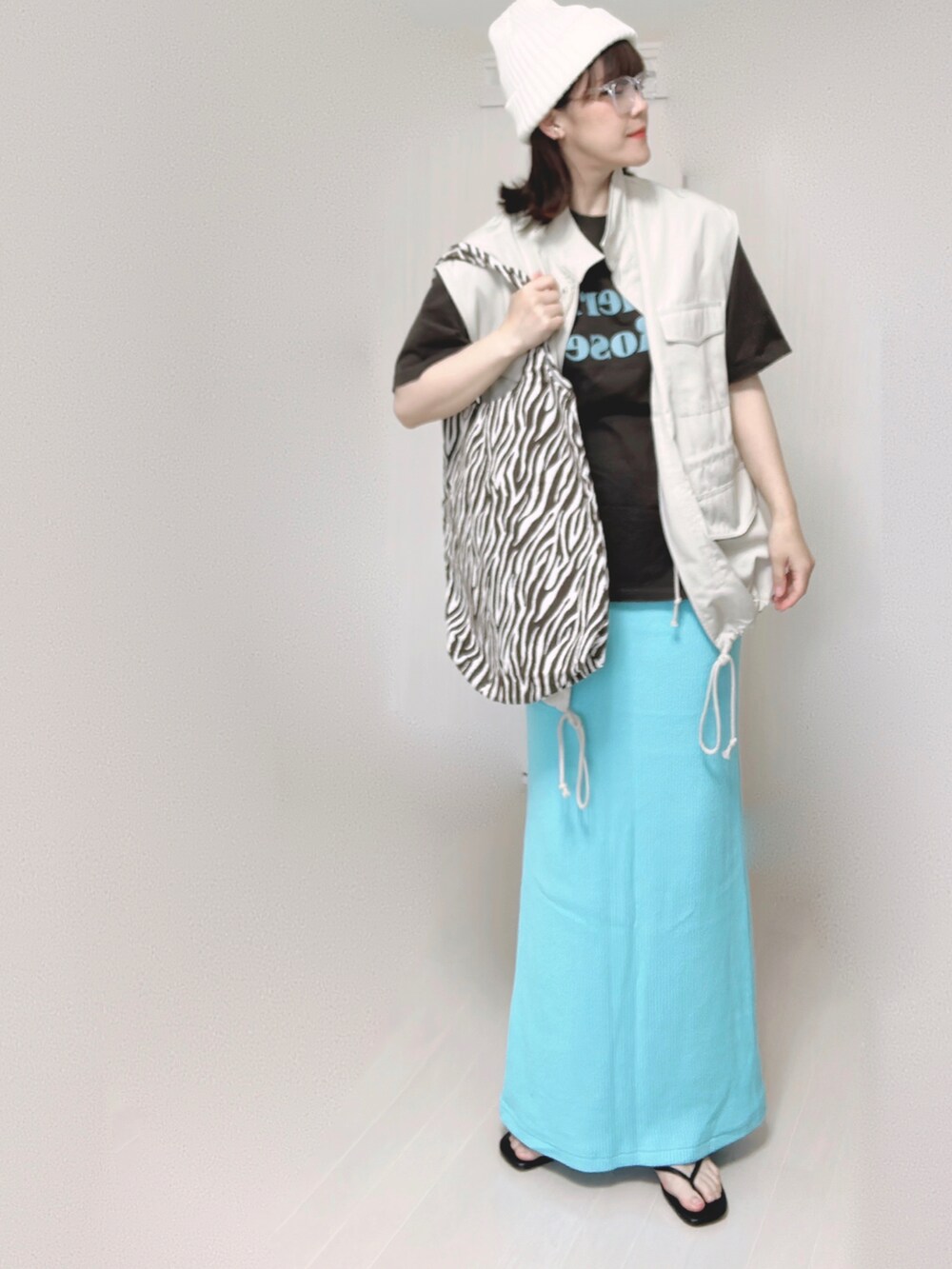 グレー系のTシャツ/カットソー、ホワイト系のベスト、ブルー系のスカートを着用したレディースの夏コーディネートの2枚目の写真