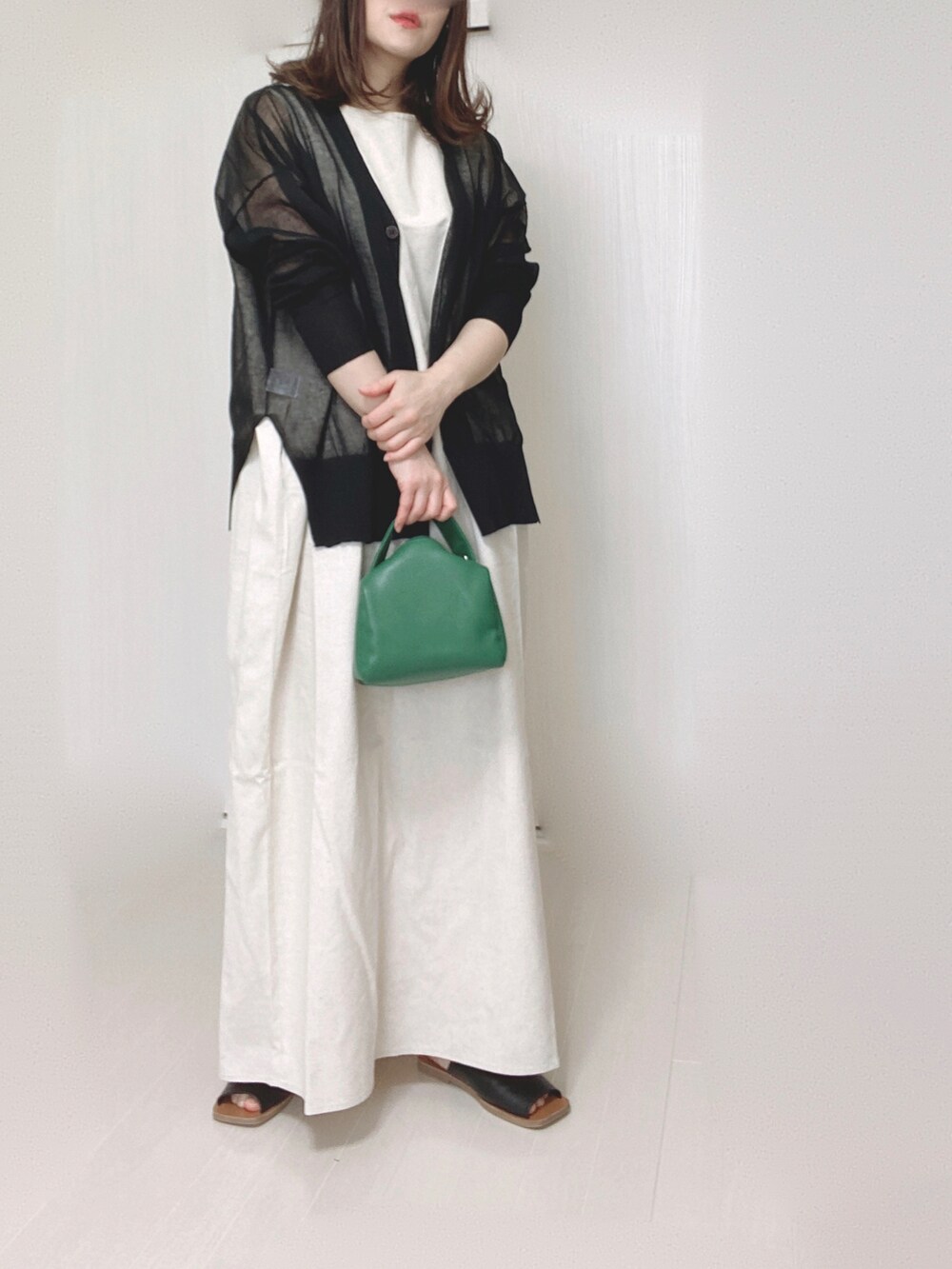 ブラック系のカーディガン/ボレロ、ホワイト系のワンピース、ブラック系のサンダルを着用したレディースの春コーディネートの2枚目の写真