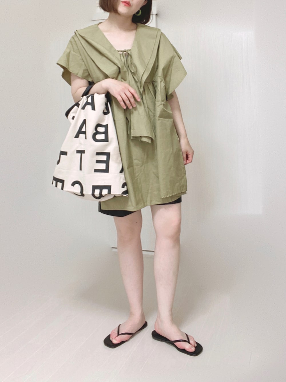 グリーン系のチュニック、ブラック系のその他パンツ、ホワイト系のトートバッグを着用したレディースの夏コーディネートの5枚目の写真