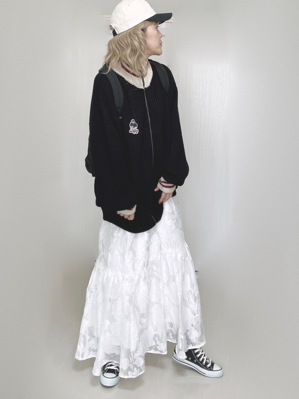 ブラック系のニット/セーター、ブラック系のバックパック/リュック、ホワイト系のスカートを着用したレディースの秋コーディネートの2枚目の写真