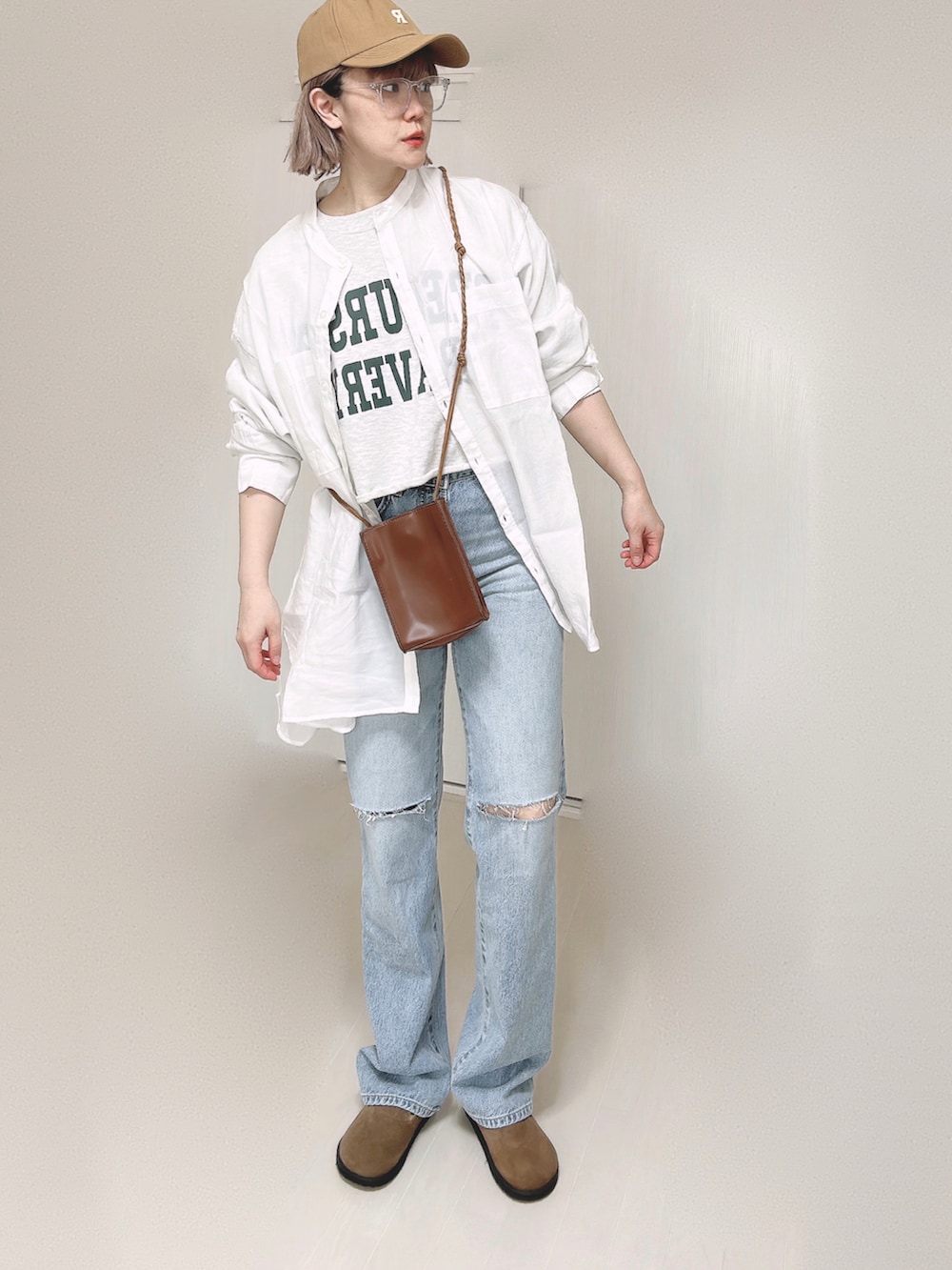 ブルー系のデニムパンツ、ホワイト系のシャツ/ブラウス、ブラウン系のショルダーバッグを着用したレディースの春コーディネートの2枚目の写真