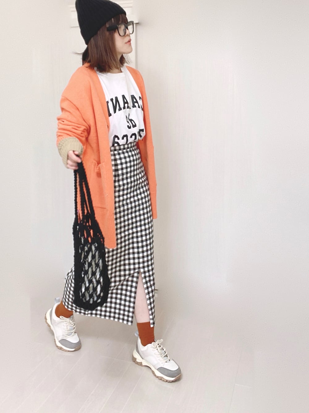 オレンジ系のカーディガン/ボレロ、ベージュ系のスニーカー、ホワイト系のTシャツ/カットソーを着用したレディースの秋コーディネートの2枚目の写真
