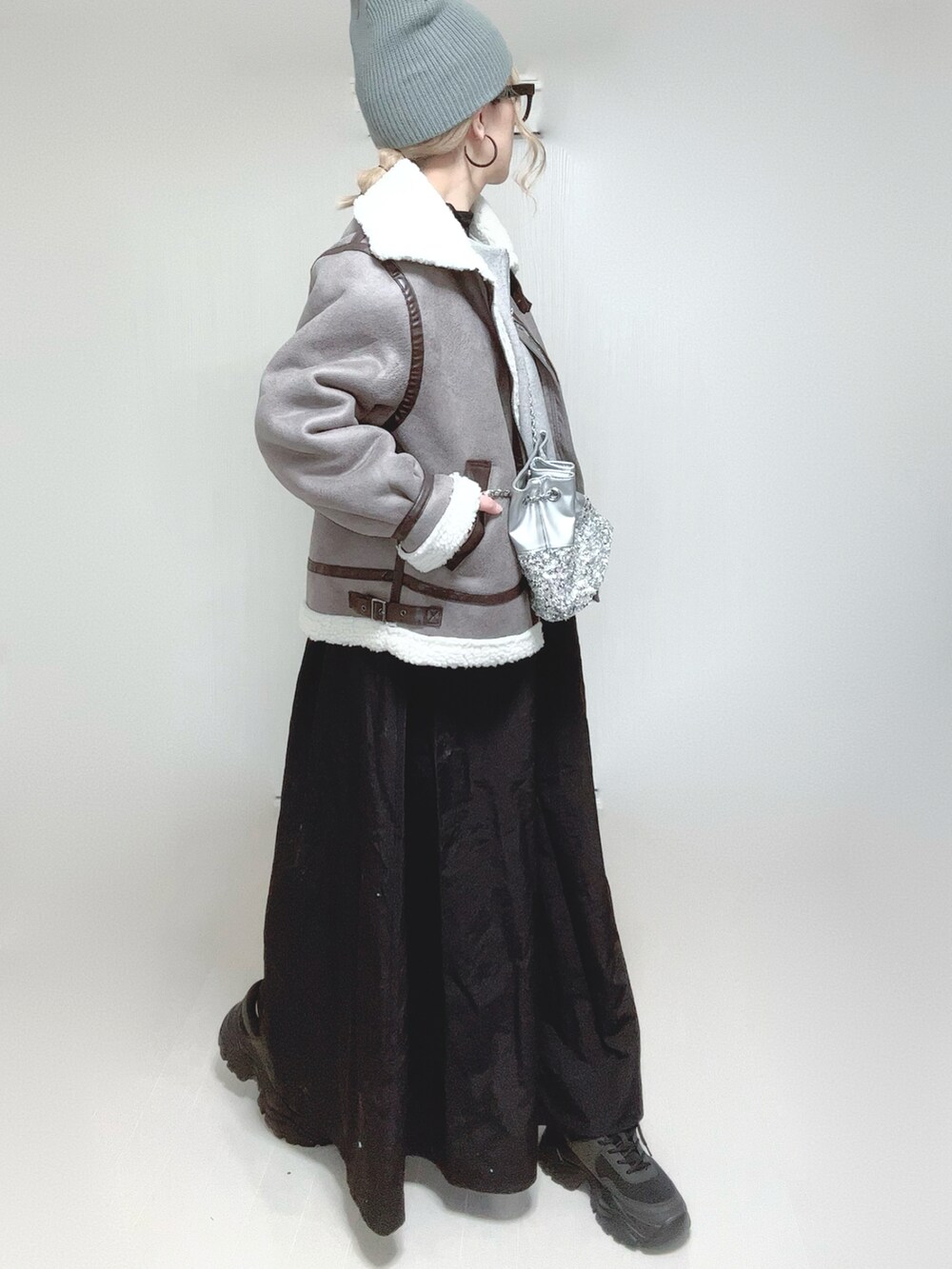 グレー系のムートンコート、グレー系のワンピース、シルバー系のショルダーバッグを着用したレディースの冬コーディネートの5枚目の写真