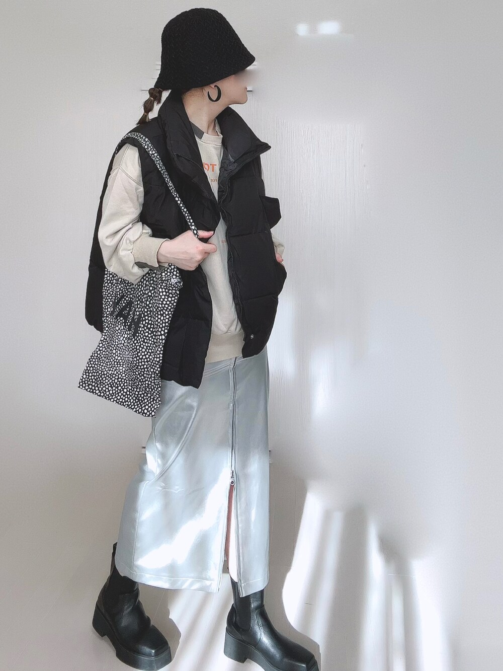 ベージュ系のスウェット、シルバー系のスカート、ブラック系のダウンベストを着用したレディースの冬コーディネートの5枚目の写真