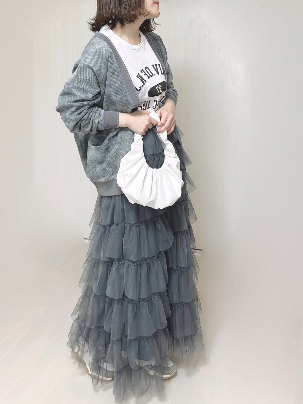 ブラック系のカーディガン/ボレロ、ホワイト系のTシャツ/カットソー、グレー系のスカートを着用したレディースの春コーディネートの5枚目の写真