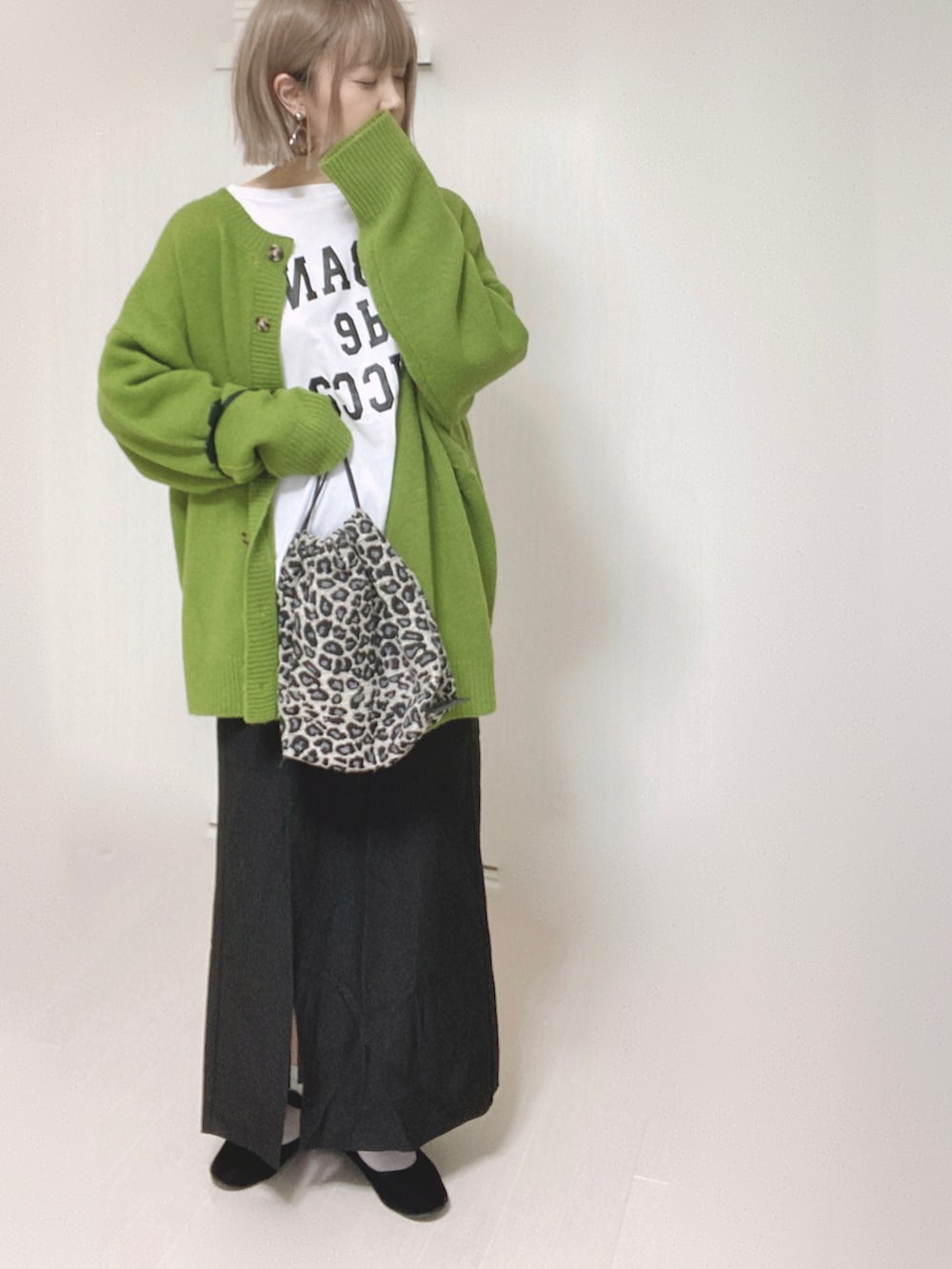 グリーン系のカーディガン/ボレロ、ホワイト系のTシャツ/カットソー、ブラック系のスカートを着用したレディースの秋コーディネートの3枚目の写真