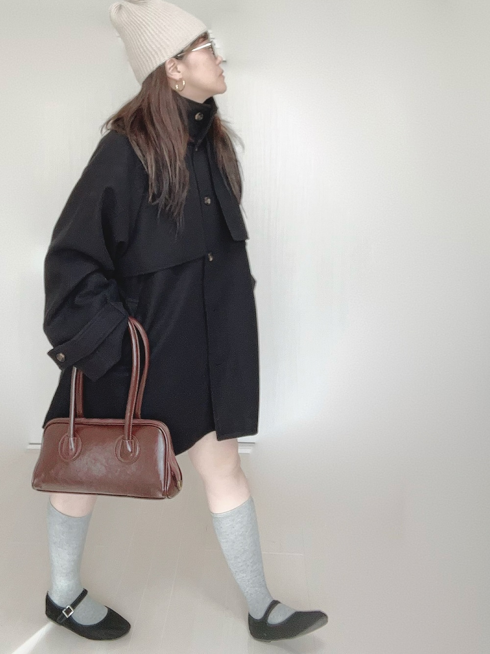 グレー系のトレンチコート、ブラウン系のショルダーバッグ、ブラック系のパンプスを着用したレディースの秋コーディネートの4枚目の写真