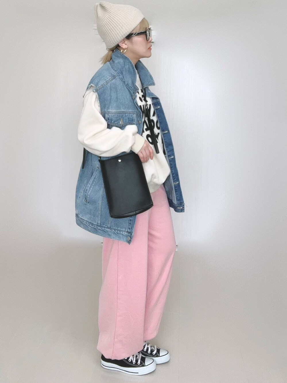 ブルー系のベスト、ブラック系のショルダーバッグ、ピンク系のスウェットパンツを着用したレディースの冬コーディネートの5枚目の写真