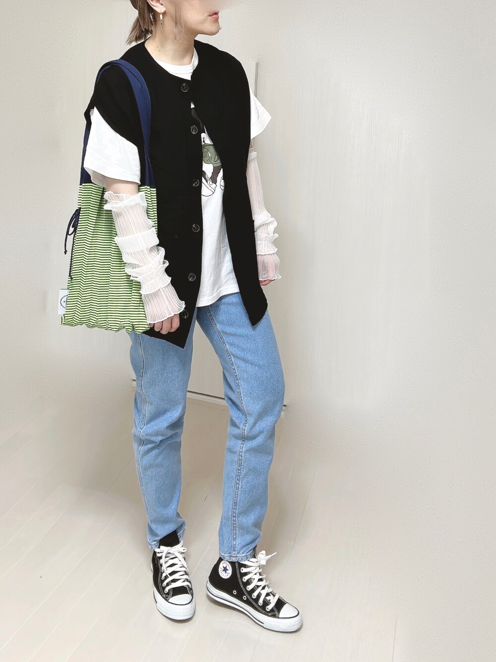 ブルー系のデニムパンツ、ブラック系のベスト、ホワイト系のTシャツ/カットソーを着用したレディースの春コーディネートの5枚目の写真