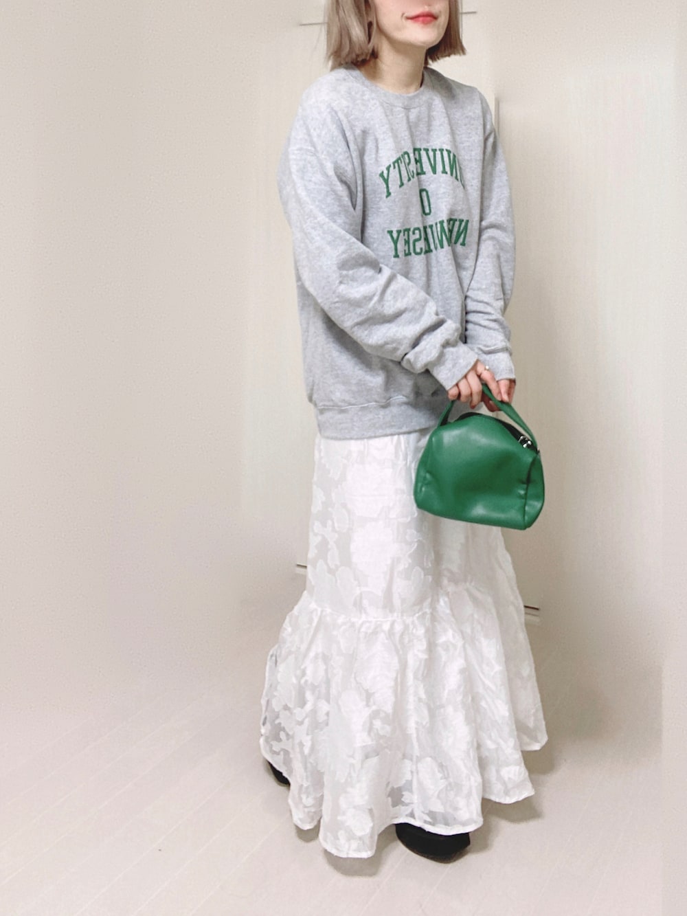 ホワイト系のスカート、グレー系のスウェット、グリーン系のハンドバッグを着用したレディースの秋コーディネートの2枚目の写真