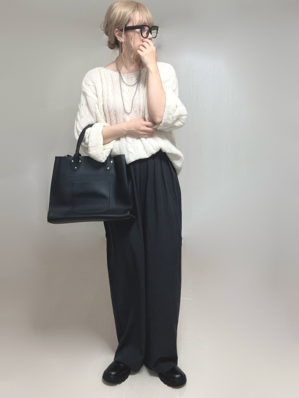ホワイト系のニット/セーター、ブラック系のブーツ、ブラック系のトートバッグを着用したレディースの夏コーディネートの2枚目の写真