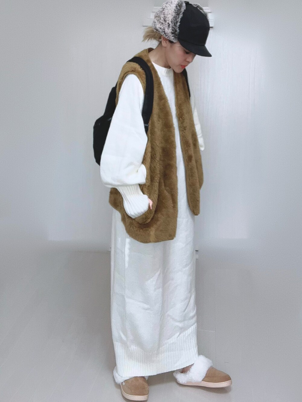 ホワイト系のワンピース、イエロー系のベスト、ブラック系のバックパック/リュックを着用したレディースの冬コーディネートの5枚目の写真