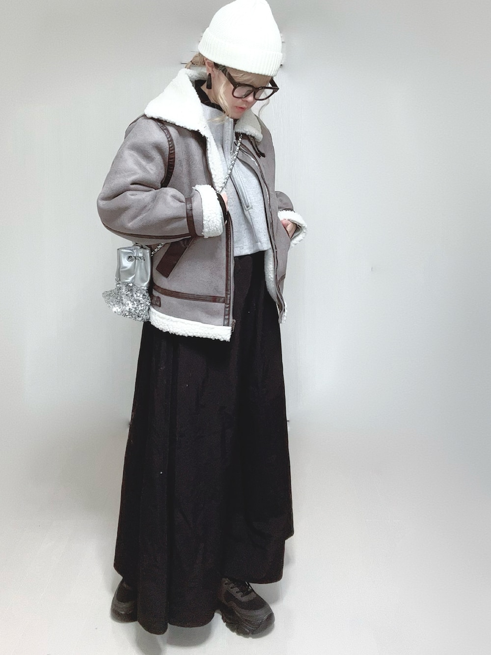 グレー系のムートンコート、グレー系のワンピース、シルバー系のショルダーバッグを着用したレディースの冬コーディネートの3枚目の写真