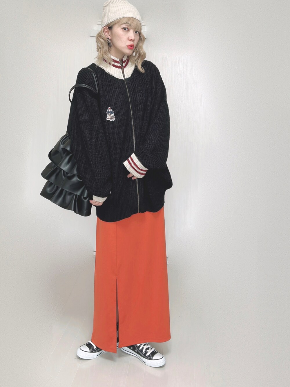 ブラック系のニット/セーター、オレンジ系のスカート、ブラック系のスニーカーを着用したレディースの秋コーディネートの5枚目の写真