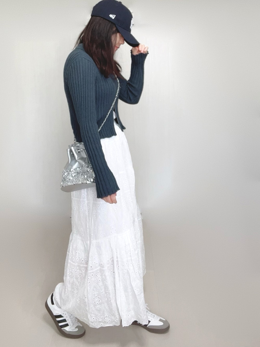グレー系のカーディガン/ボレロ、シルバー系のショルダーバッグ、ホワイト系のスカートを着用したレディースの春コーディネートの4枚目の写真