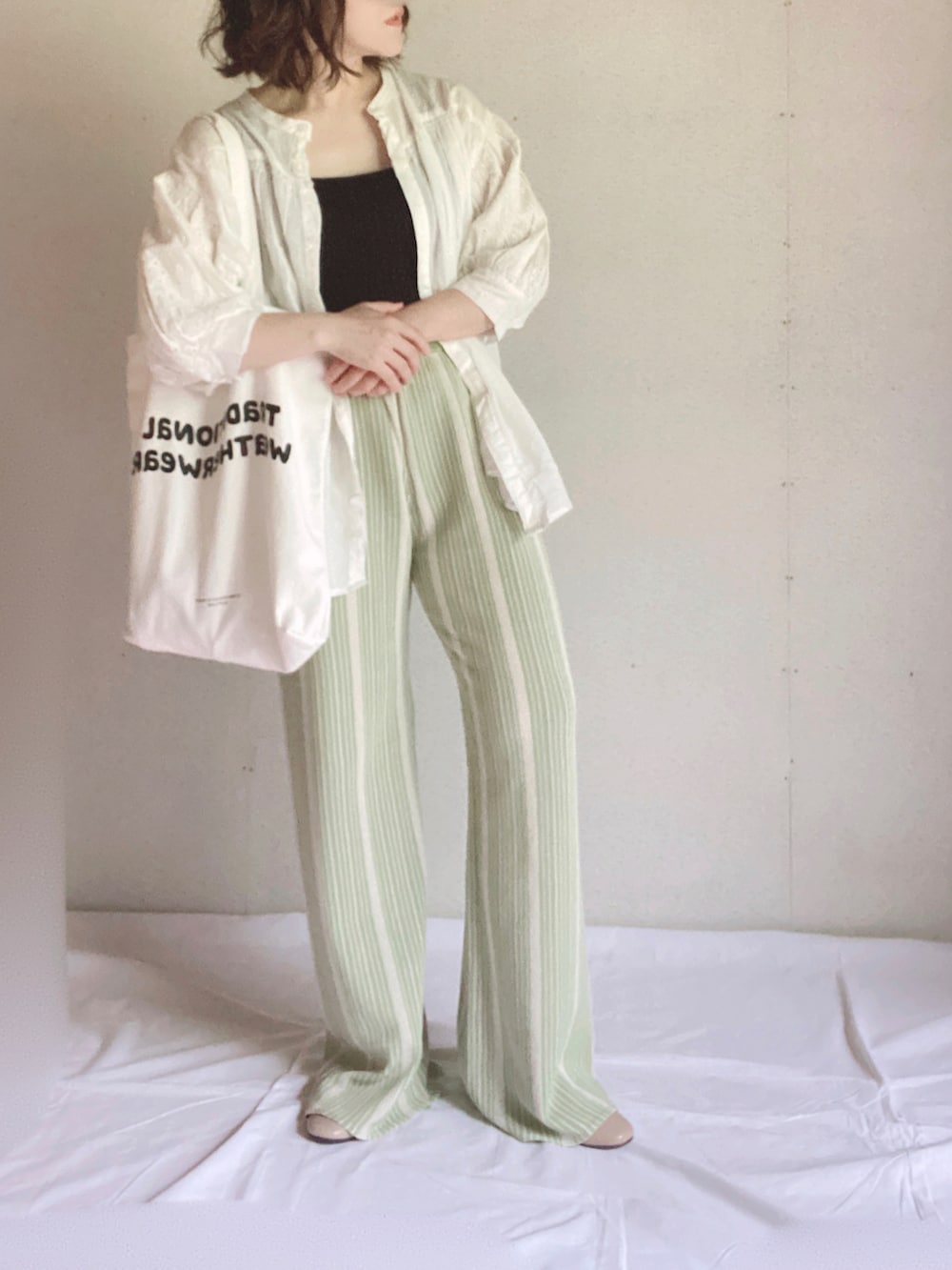 ホワイト系のシャツ/ブラウス、ホワイト系のトートバッグ、ベージュ系のパンプスを着用したレディースの夏コーディネートの4枚目の写真