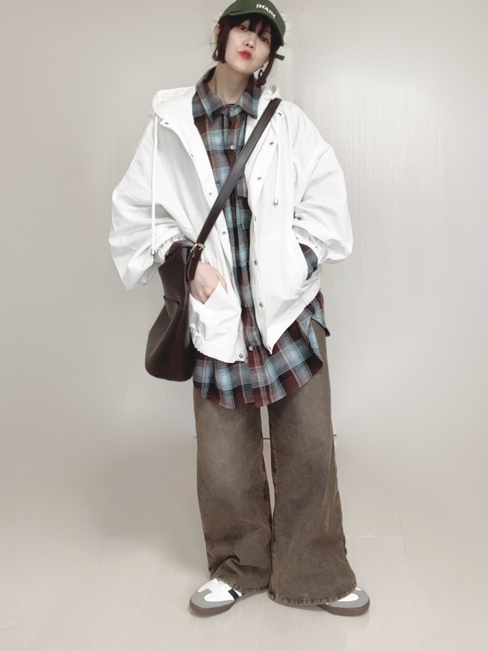 ホワイト系のマウンテンパーカー、ブラウン系のシャツ/ブラウス、ブラック系のデニムパンツを着用したレディースの春コーディネートの3枚目の写真