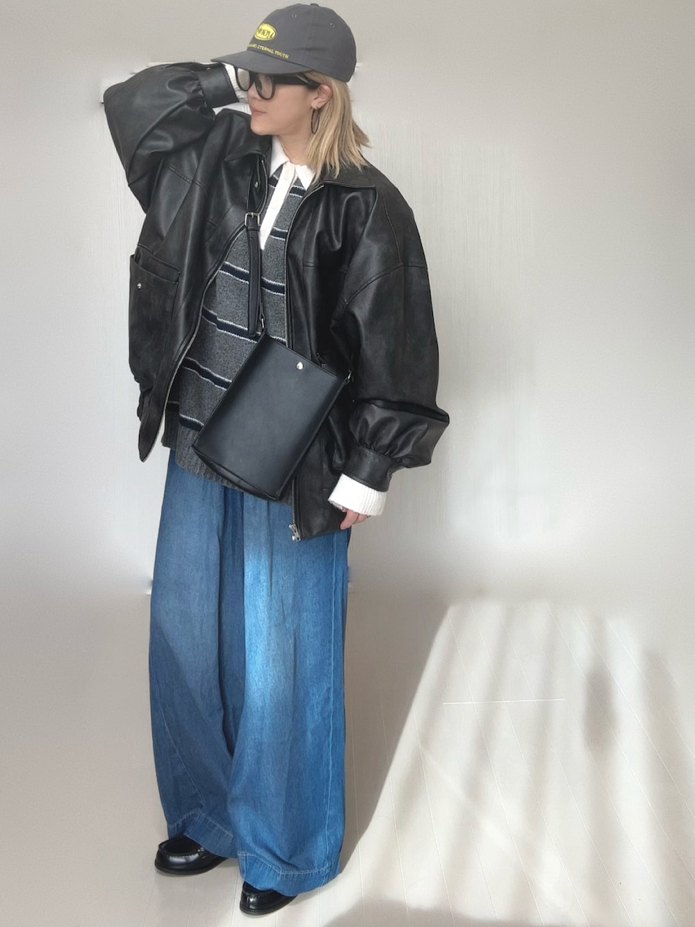 グレー系のニット/セーター、ブラック系のブルゾン、ブルー系のデニムパンツを着用したレディースの冬コーディネートの3枚目の写真