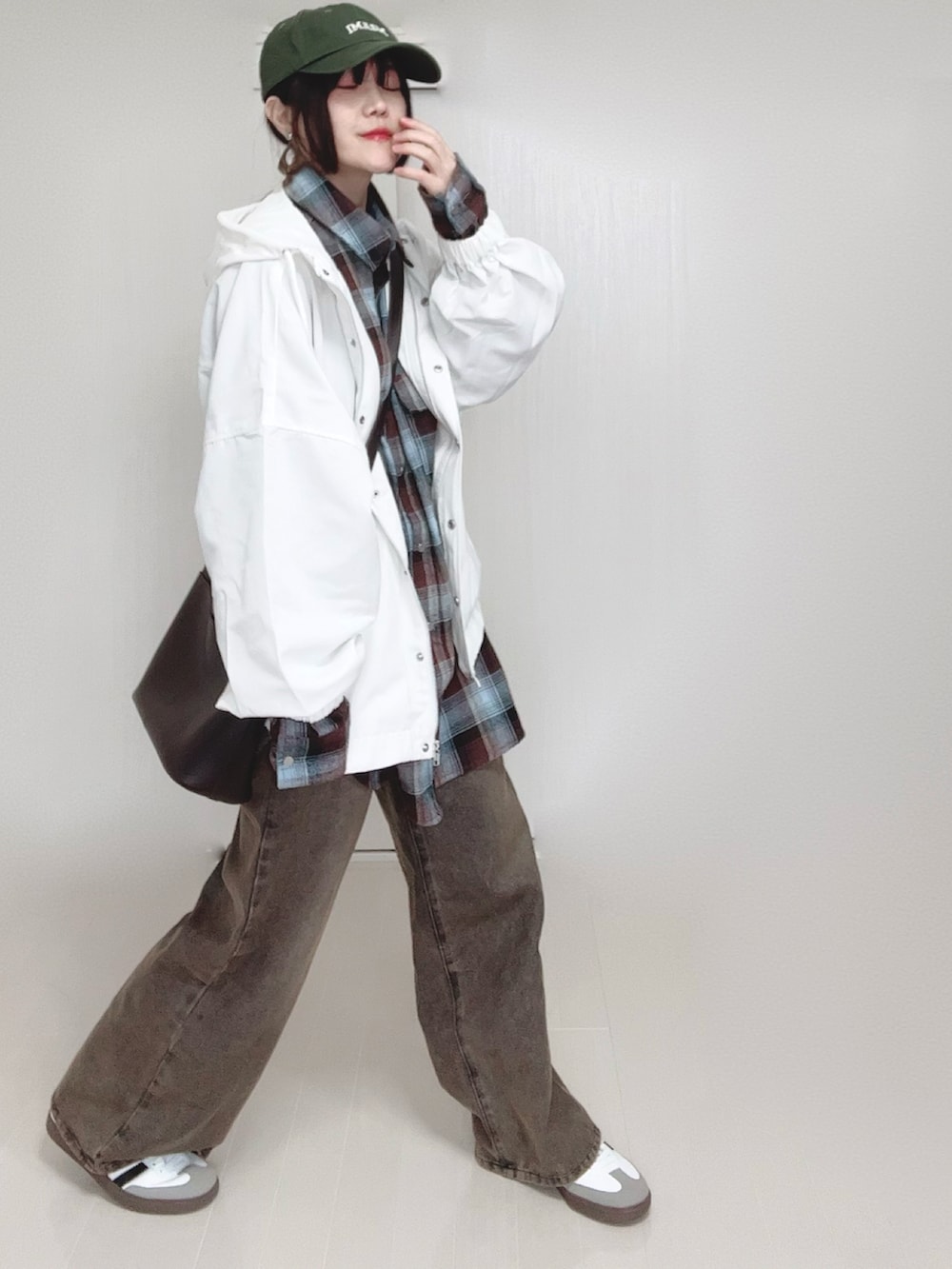 ホワイト系のマウンテンパーカー、ブラウン系のシャツ/ブラウス、ブラック系のデニムパンツを着用したレディースの春コーディネートの2枚目の写真