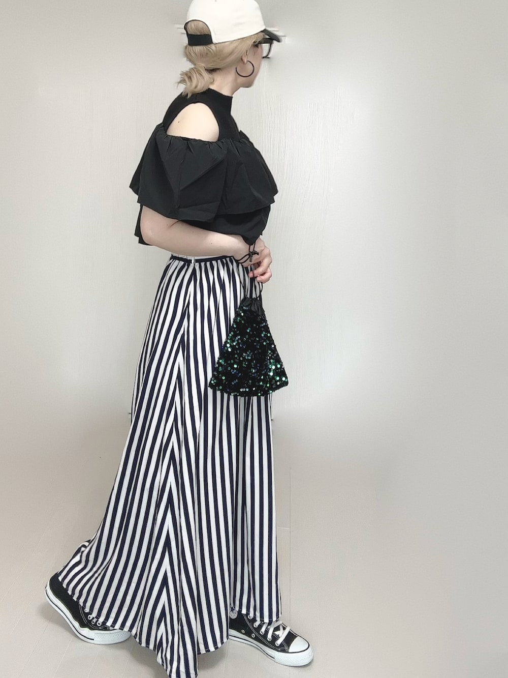 ブルー系のスカート、ブラック系のスニーカー、ブラック系のキャップを着用したレディースの春コーディネートの2枚目の写真