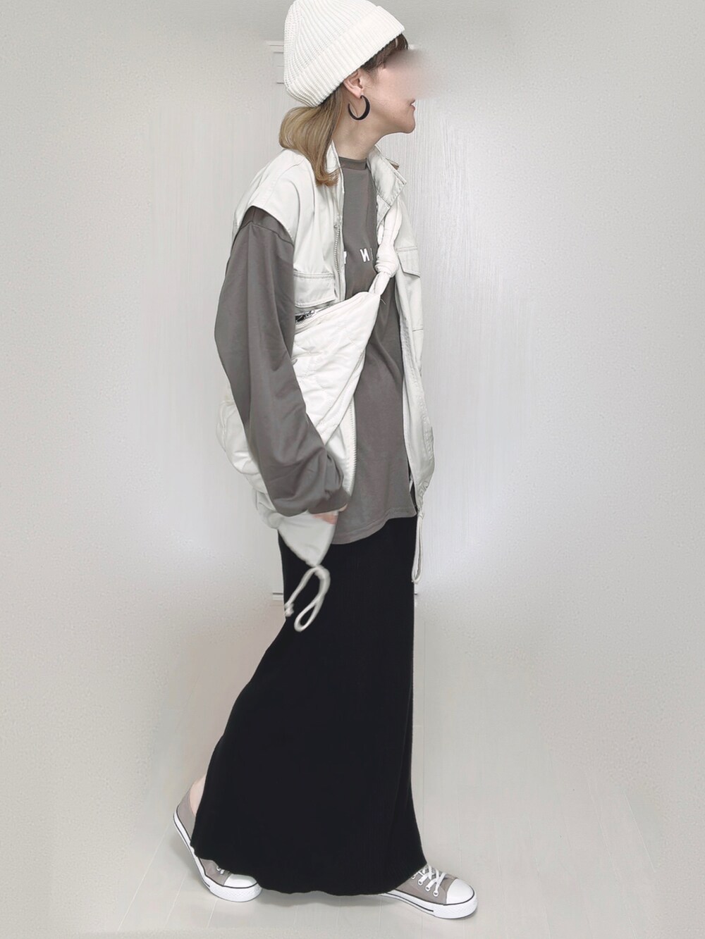 ホワイト系のショルダーバッグ、ホワイト系のベスト、ブラック系のスカートを着用したレディースの秋コーディネートの2枚目の写真