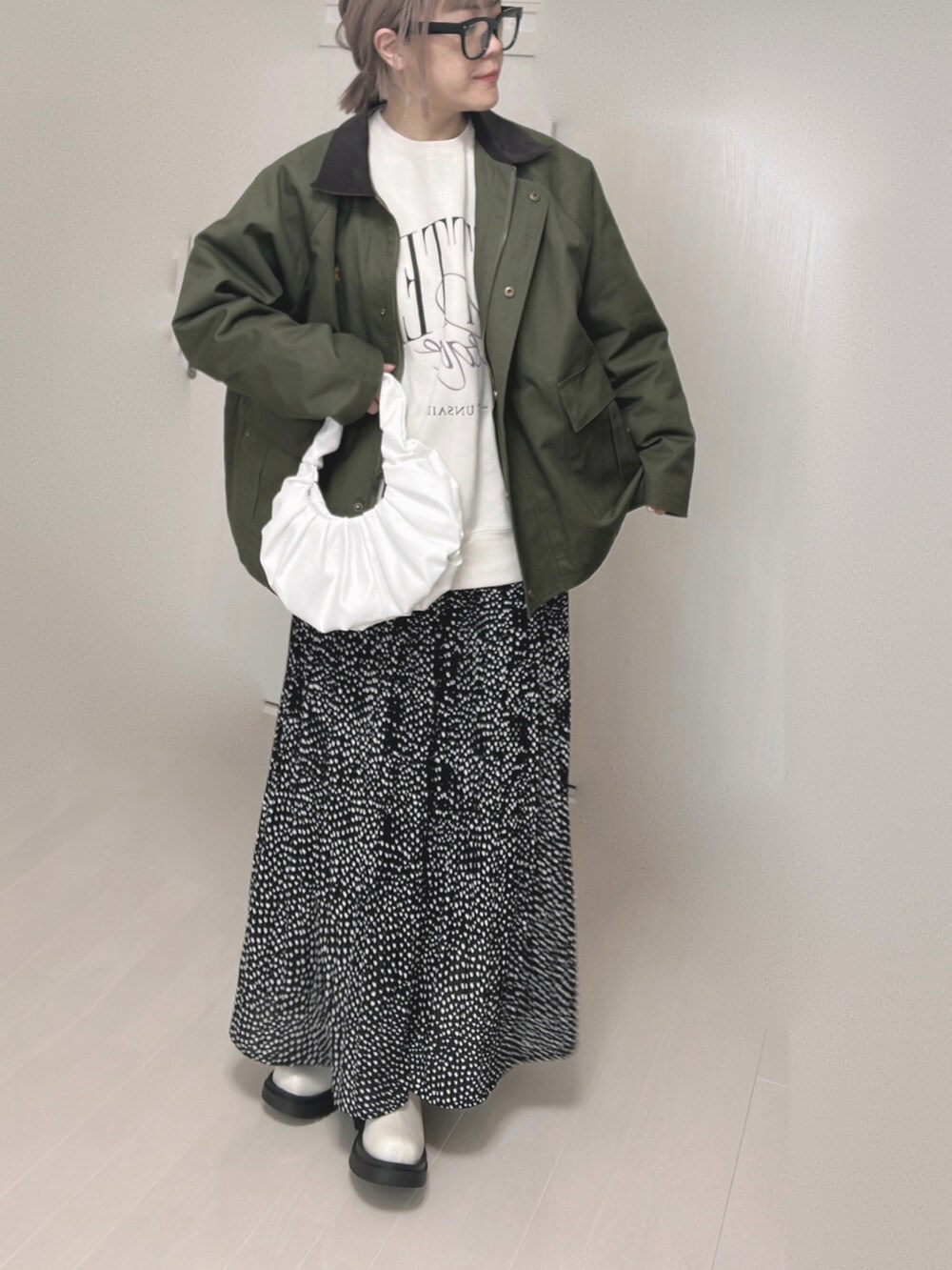 グリーン系のカバーオール、ブラック系のスカート、ホワイト系のブーツを着用したレディースの冬コーディネートの5枚目の写真