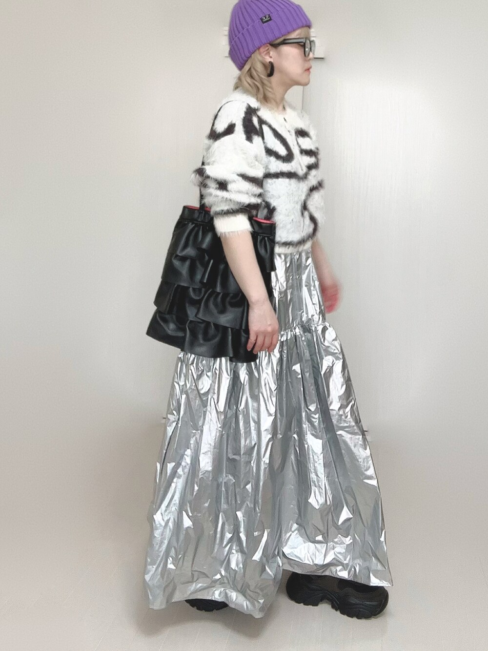 ホワイト系のカーディガン/ボレロ、シルバー系のスカート、ブラック系のスニーカーを着用したレディースの春コーディネートの4枚目の写真