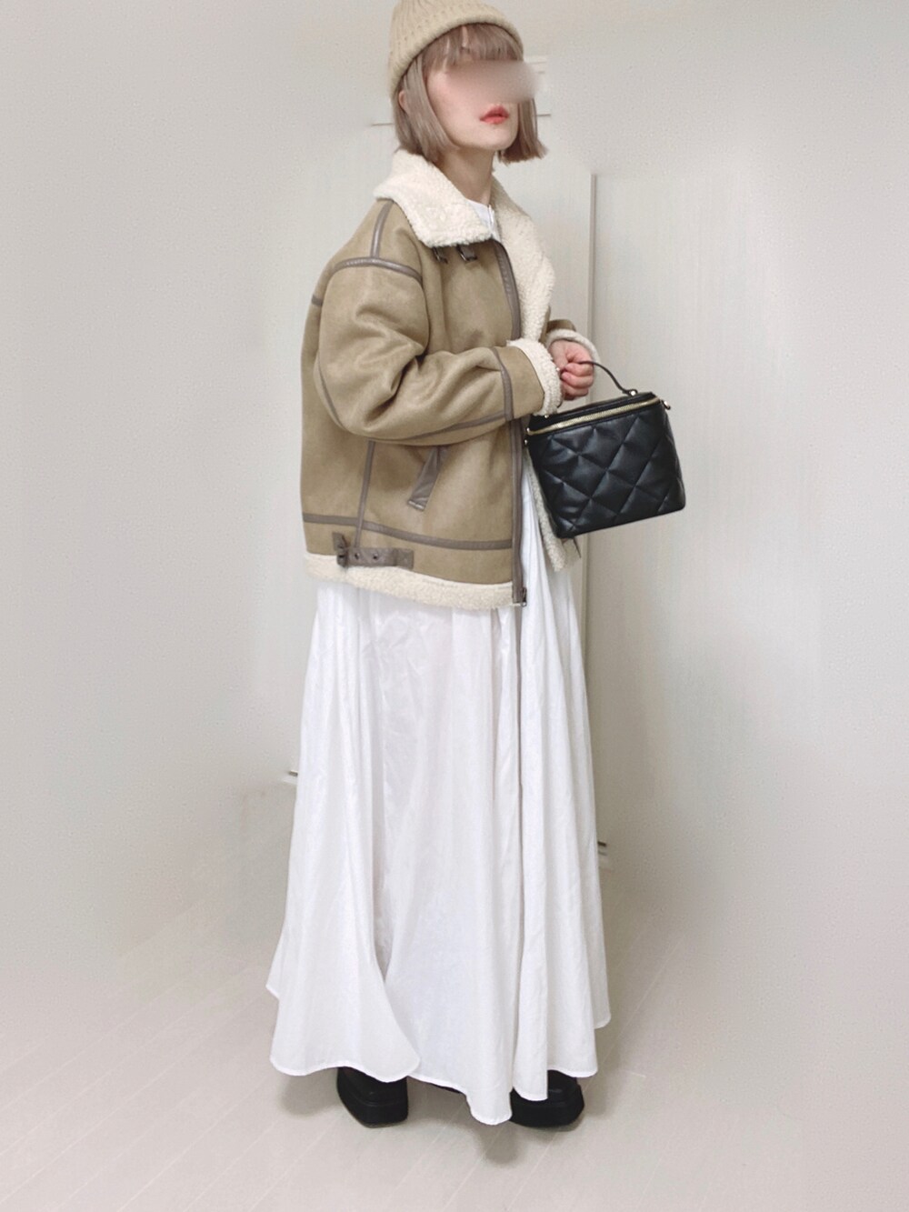 ベージュ系のムートンコート、ホワイト系のシャツワンピース、ブラック系のショルダーバッグを着用したレディースの秋コーディネートの5枚目の写真