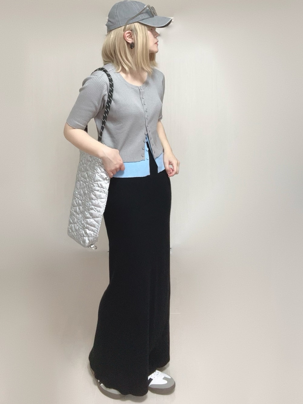 グレー系のニット/セーター、シルバー系のトートバッグ、ブラック系のスカートを着用したレディースの春コーディネートの3枚目の写真