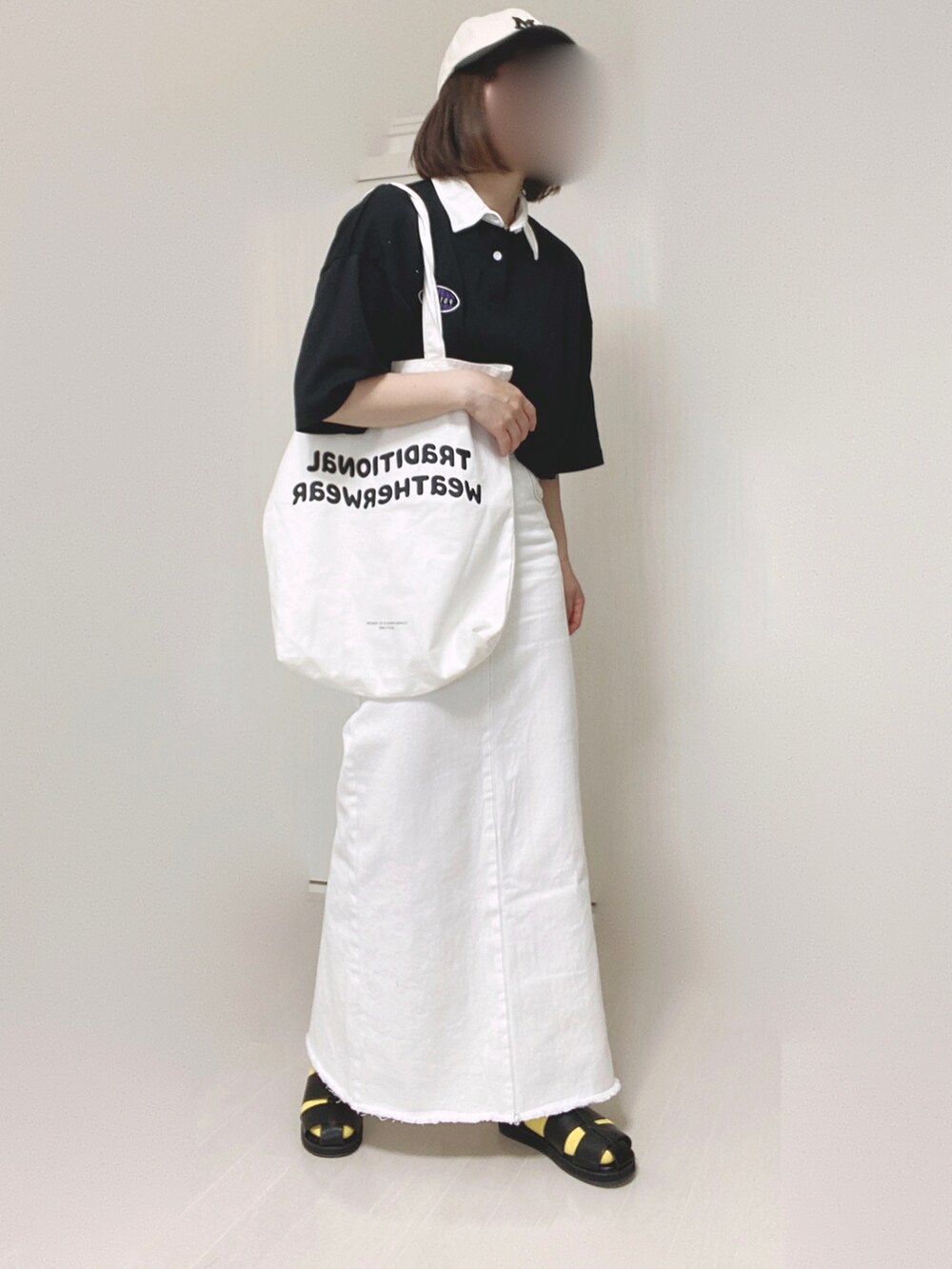 ベージュ系のデニムスカート、ホワイト系のトートバッグ、ブラック系のサンダルを着用したレディースの夏コーディネートの2枚目の写真