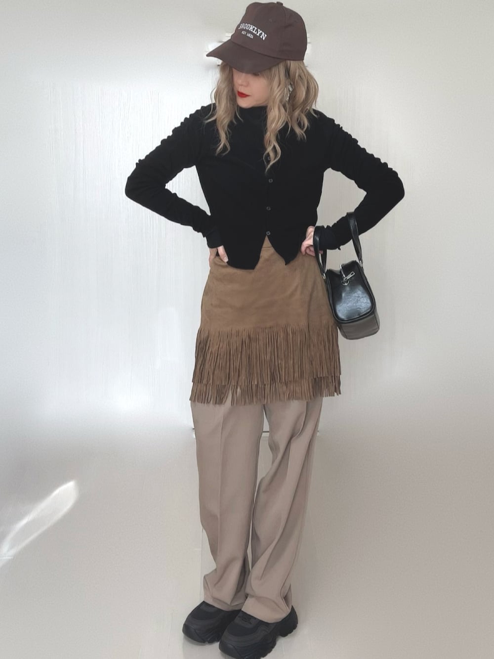 ブラック系のカーディガン/ボレロ、ブラック系のTシャツ/カットソー、ベージュ系のスカートを着用したレディースの冬コーディネートの3枚目の写真