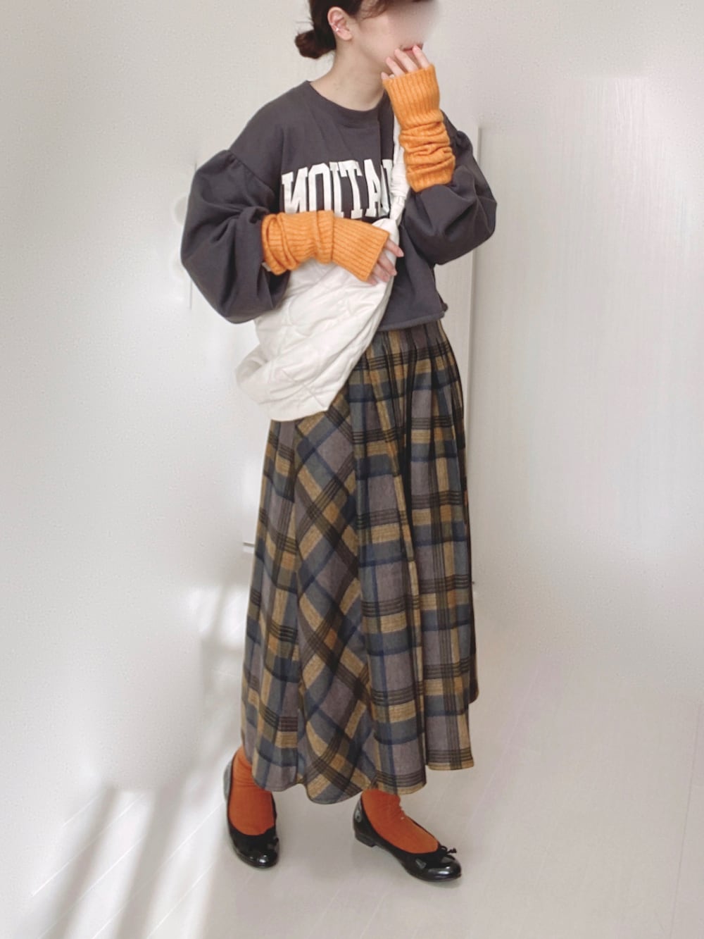 ホワイト系のショルダーバッグ、イエロー系のスカート、ブラック系のバレエシューズを着用したレディースの冬コーディネートの2枚目の写真