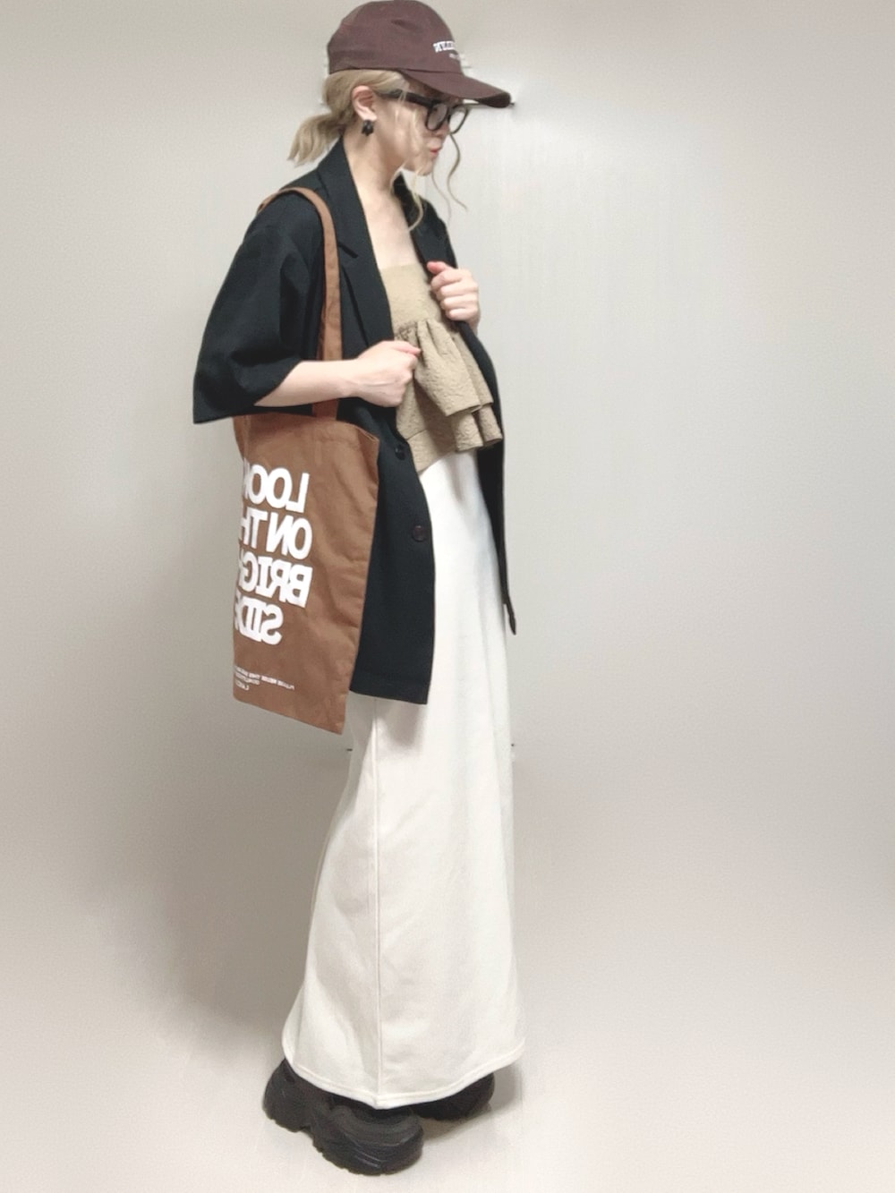 ブラック系のテーラードジャケット、ベージュ系のキャミソール、ブラック系のスニーカーを着用したレディースの夏コーディネートの2枚目の写真