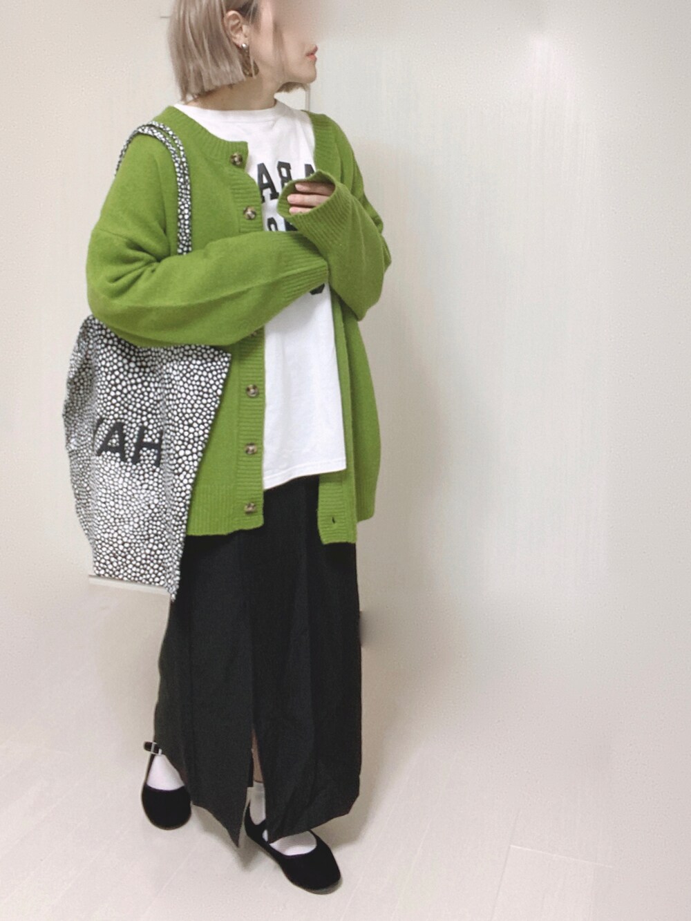 グリーン系のカーディガン/ボレロ、ホワイト系のTシャツ/カットソー、ブラック系のスカートを着用したレディースの秋コーディネートの5枚目の写真