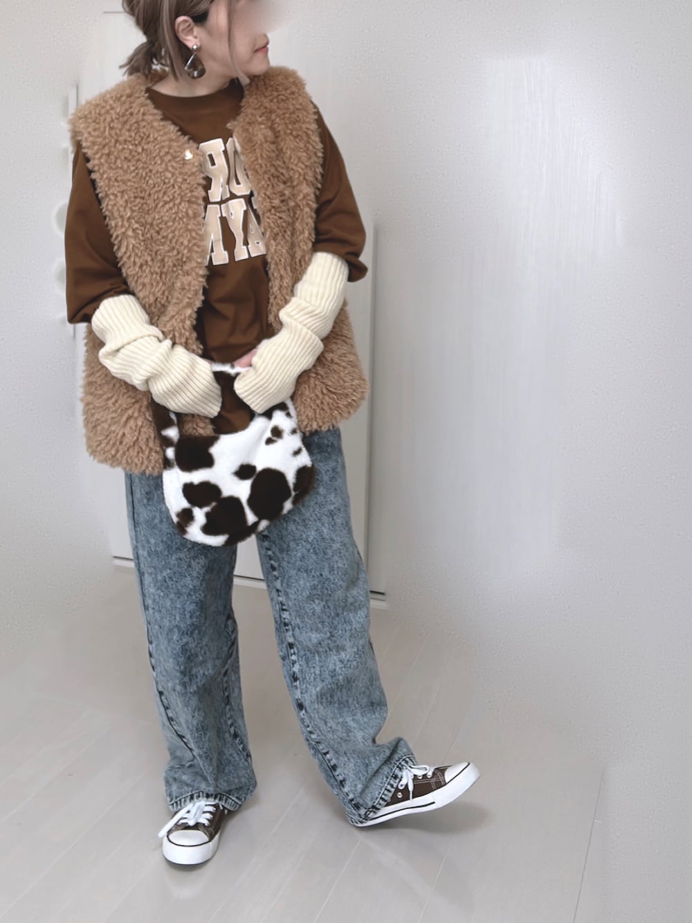 イエロー系のベスト、ブラウン系のTシャツ/カットソー、ブルー系のデニムパンツを着用したレディースの春コーディネートの3枚目の写真