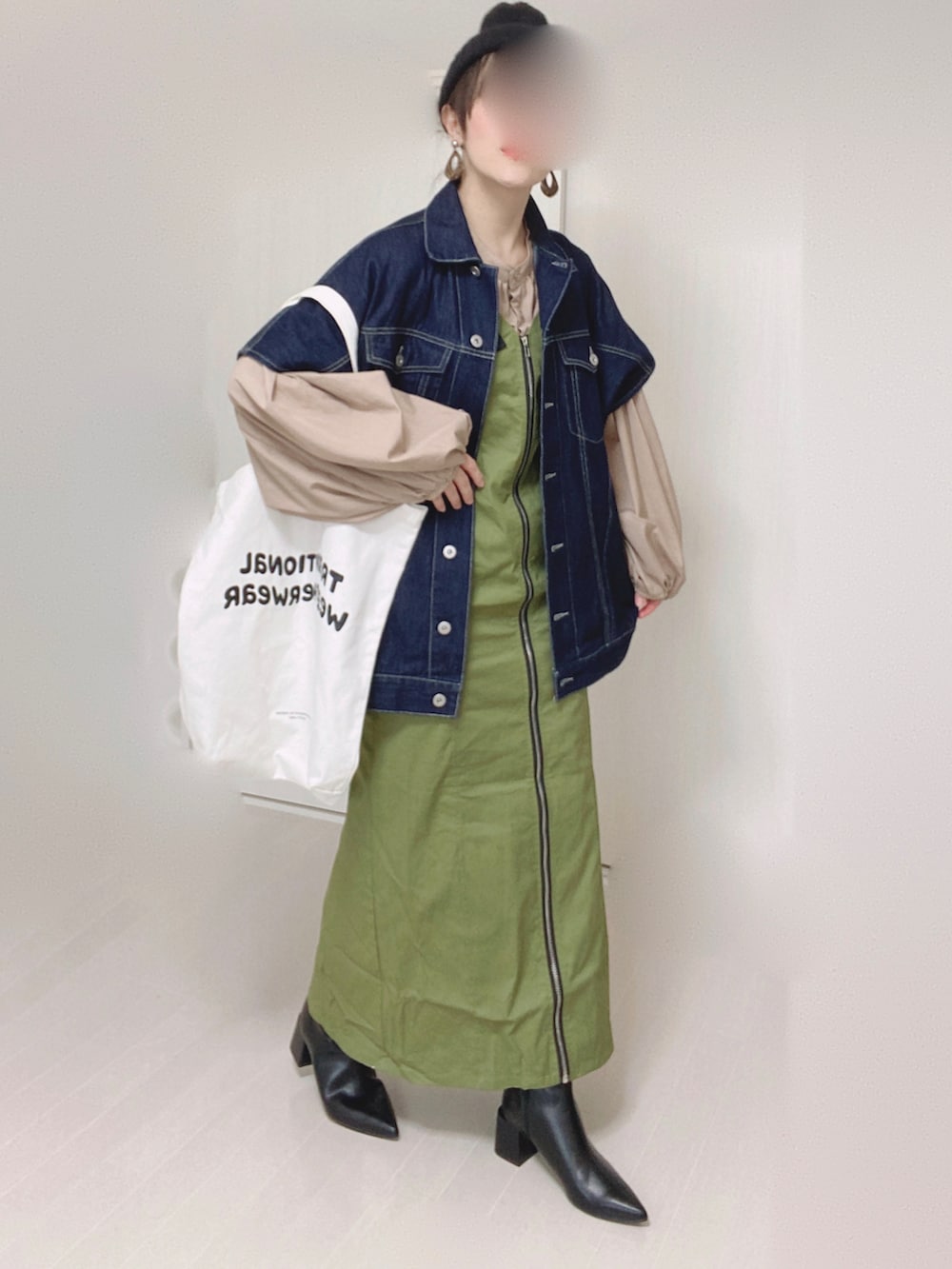 グリーン系のジャンパースカート、ブルー系のベスト、ベージュ系のシャツ/ブラウスを着用したレディースの秋コーディネートの2枚目の写真